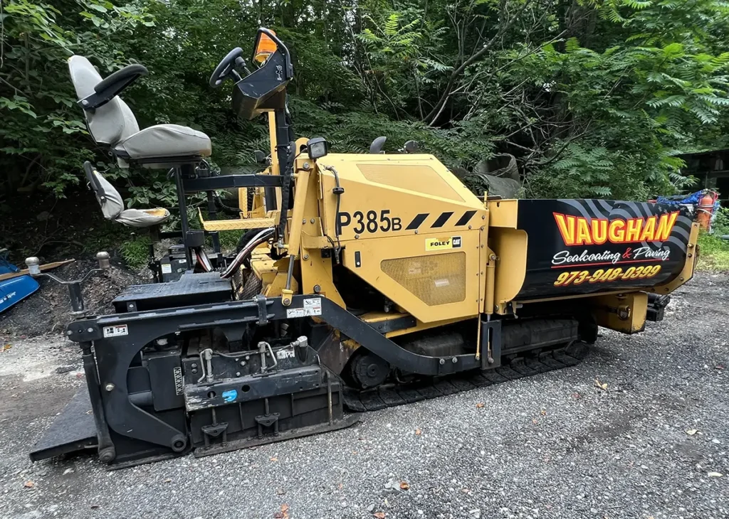 Yellow CAT asphalt paver with black Vaughan Sealcoating & Paving graphics on the side
