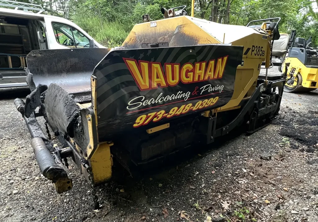 Yellow CAT asphalt paver with black Vaughan Sealcoating & Paving graphics on the side