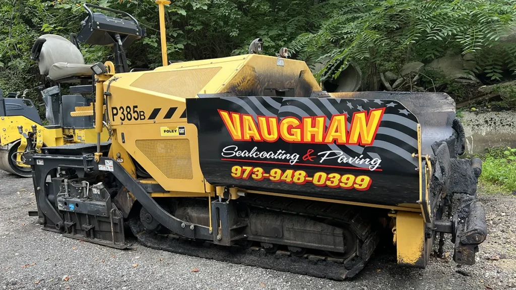Yellow CAT asphalt paver with black Vaughan Sealcoating & Paving graphics on the side