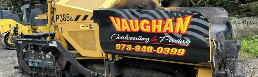 Yellow CAT asphalt paver with black Vaughan Sealcoating & Paving graphics on the side